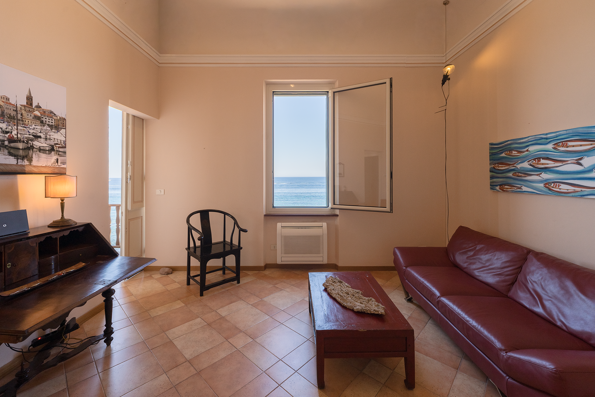 Zona relax con affaccio sul mare Soggiorno con divano in pelle, scrittoio e finestra vista mare nell’appartamento Le Viste