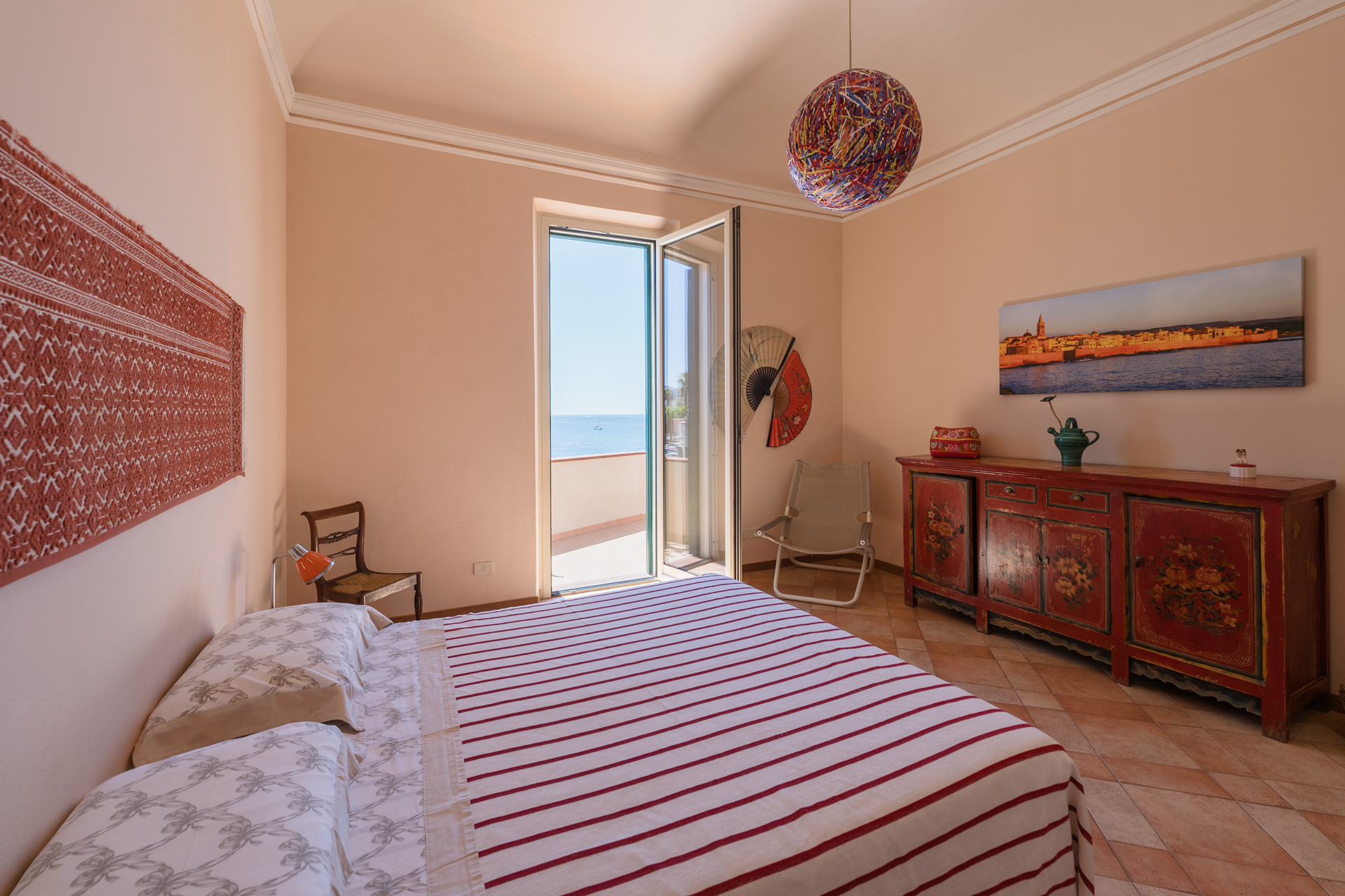 Camera matrimoniale con terrazza, cassettiera decorata e arredi artigianali nell’appartamento Le Viste