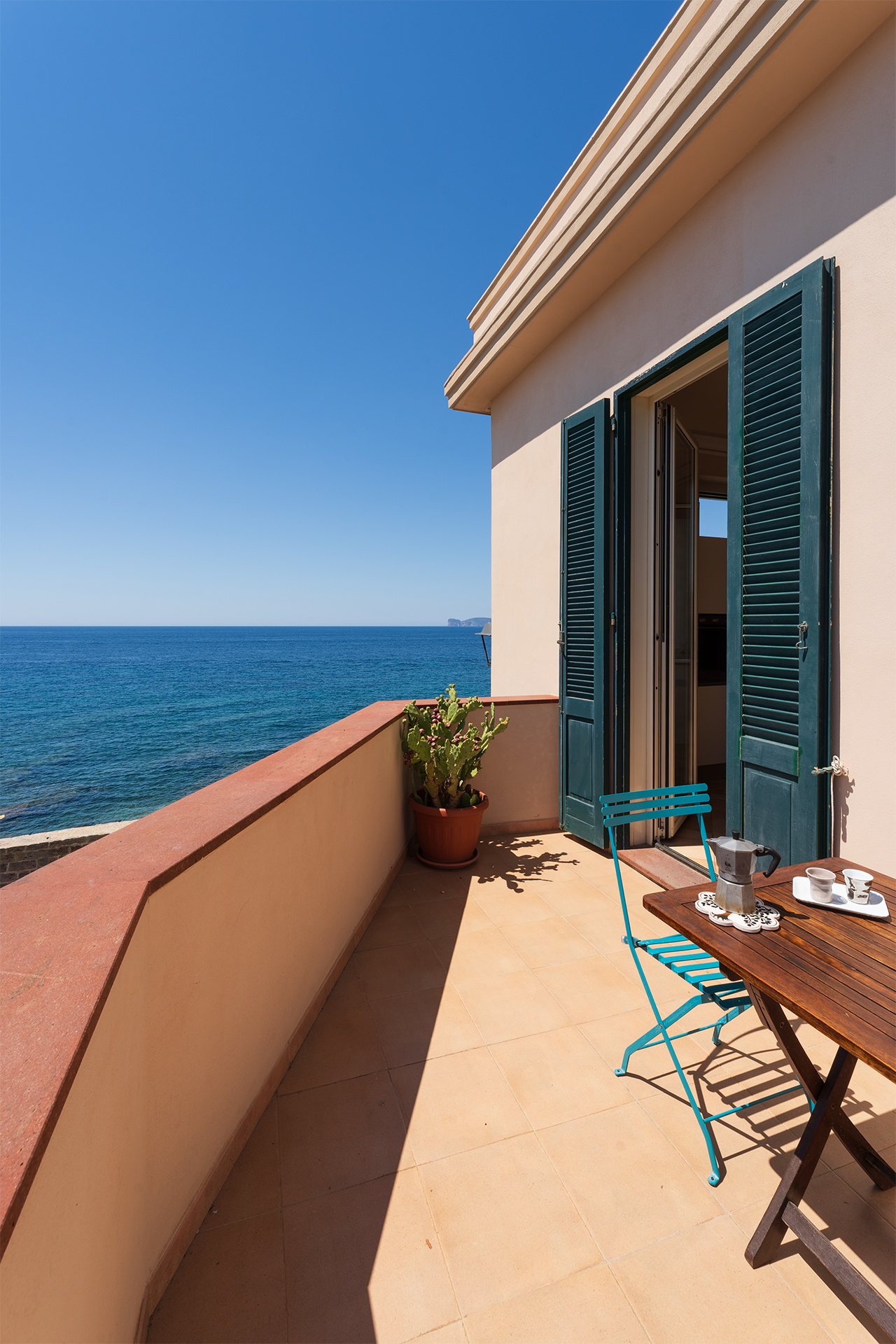 Terrazza privata vista mare Terrazza privata con tavolo da colazione, persiane verdi e vista sul mare di Alghero