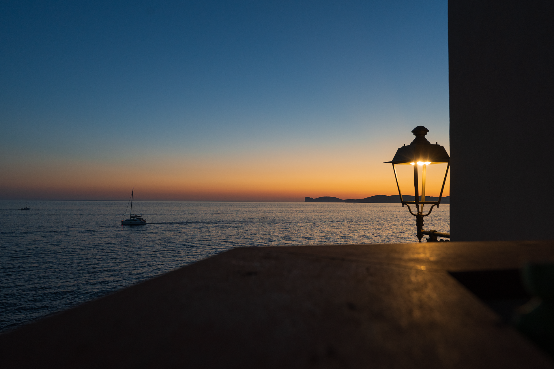 Tramonto con barca a vela Tramonto sul mare con barca a vela e lampione davanti all’appartamento Le Viste
