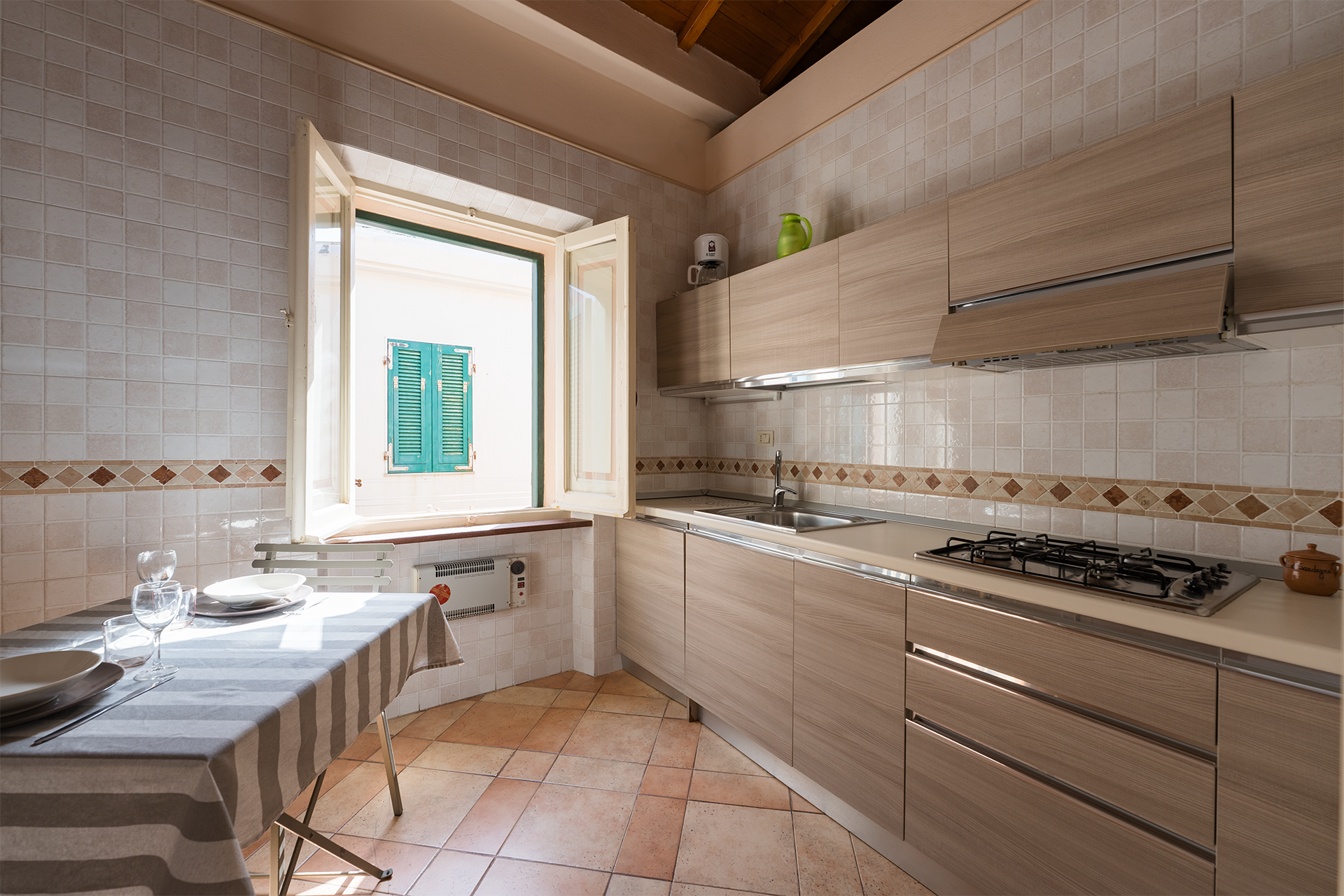 Cucina moderna e attrezzata Cucina moderna con piano cottura, lavello e tavolo apparecchiato a L’Attichetto