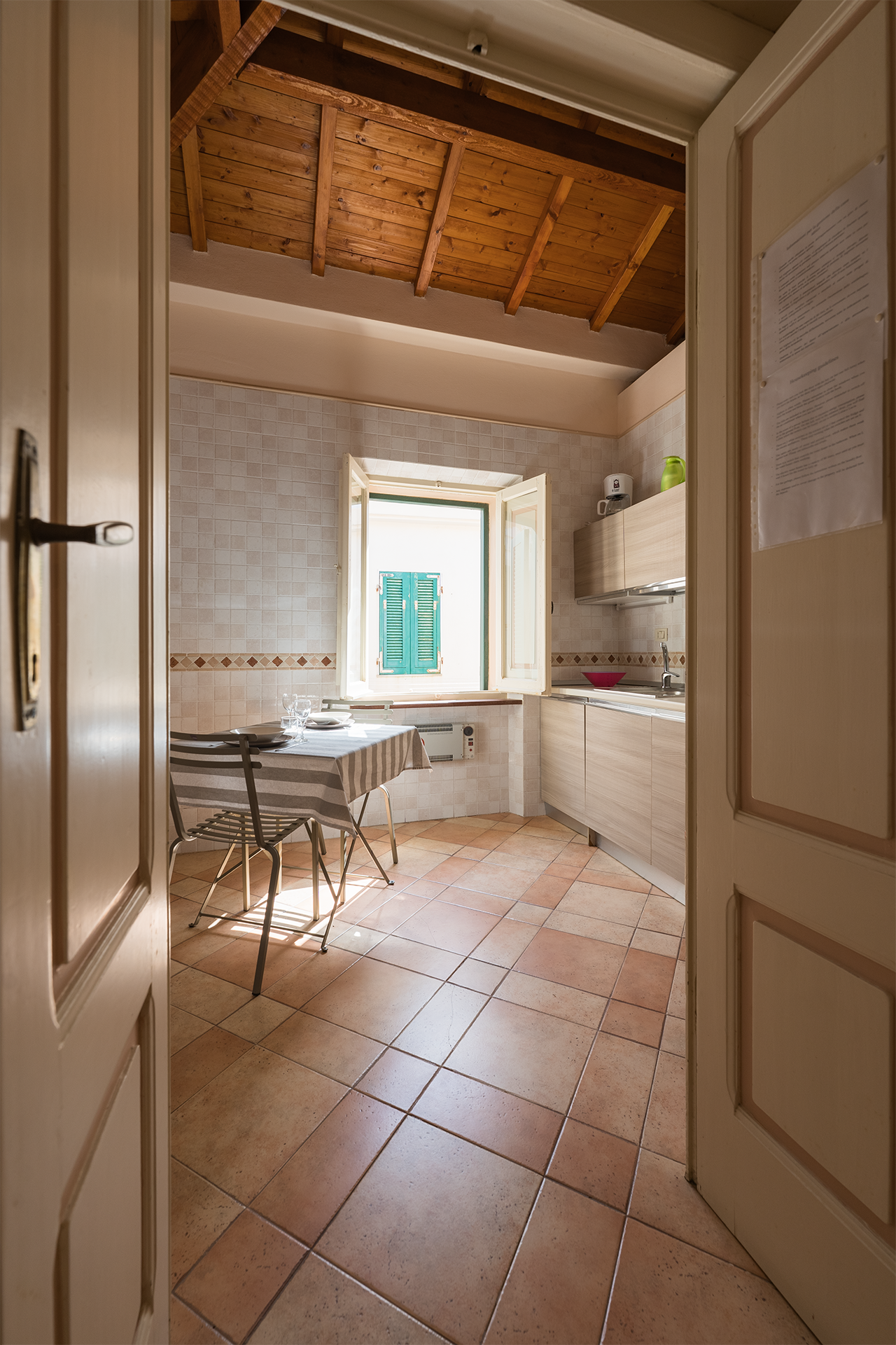 Ingresso della cucina con soffitto in legno Ingresso della cucina con soffitto in legno e finestra luminosa nell’appartamento L’Attichetto