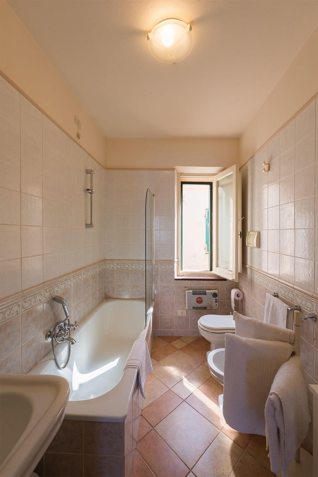 Bagno con vasca e finestra Bagno completo con vasca, sanitari e finestra nell’appartamento L’Attichetto