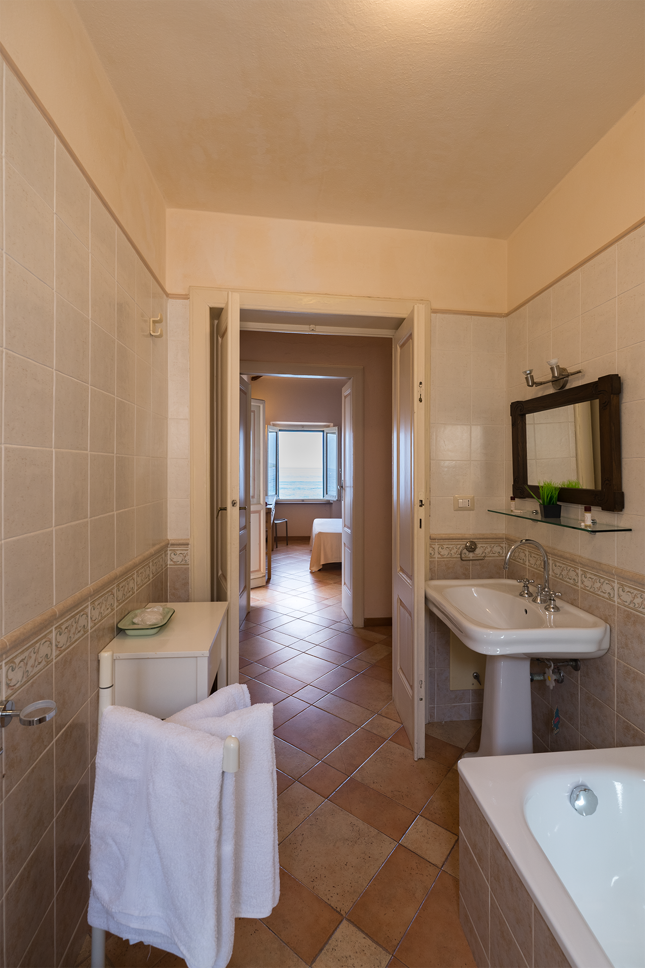 Lavabo e ingresso del bagno Bagno con lavabo, vasca e vista verso la camera affacciata sul mare a L’Attichetto