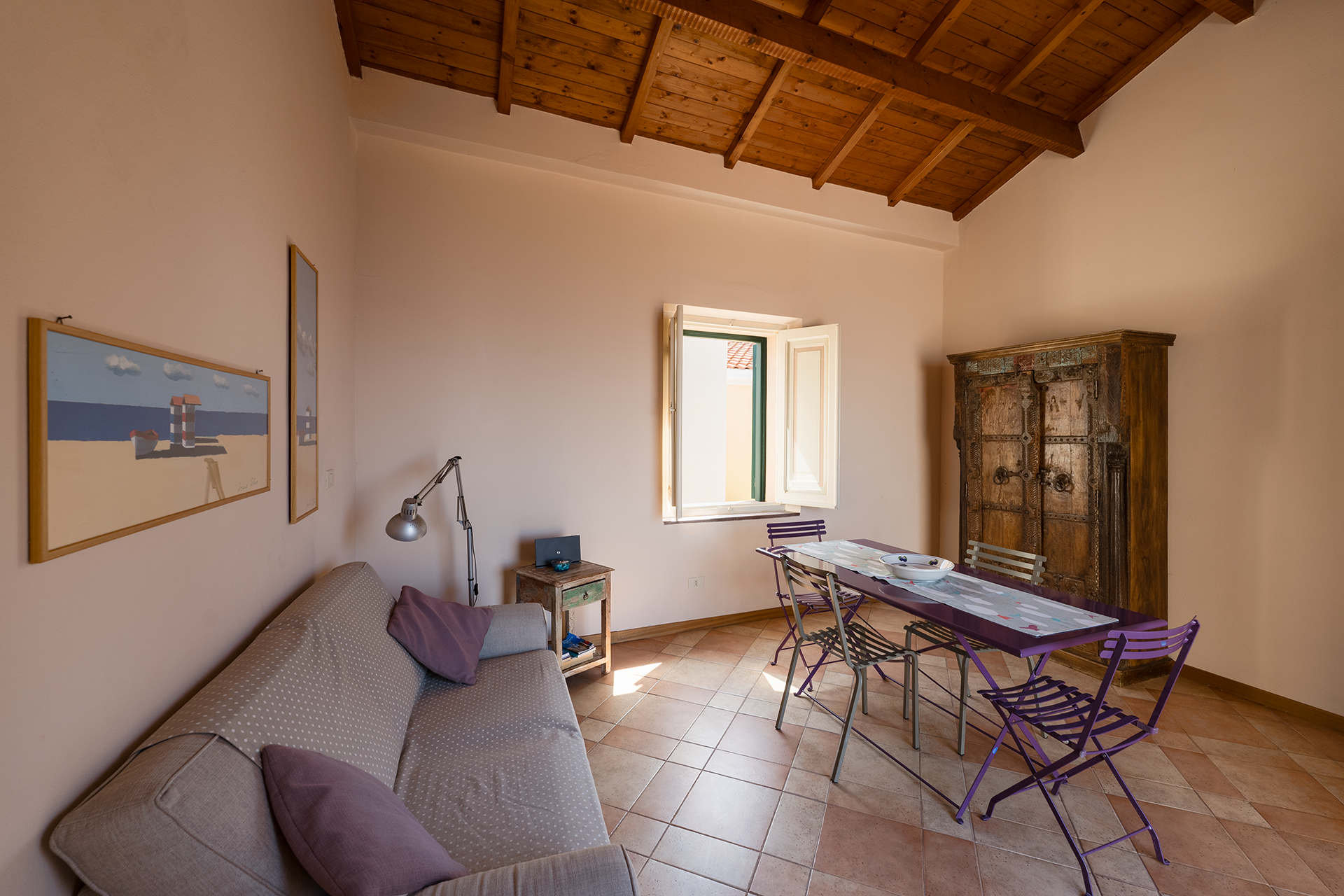 Soggiorno con zona pranzo Soggiorno con divano, tavolo da pranzo e soffitto in legno nell’appartamento L’Attichetto
